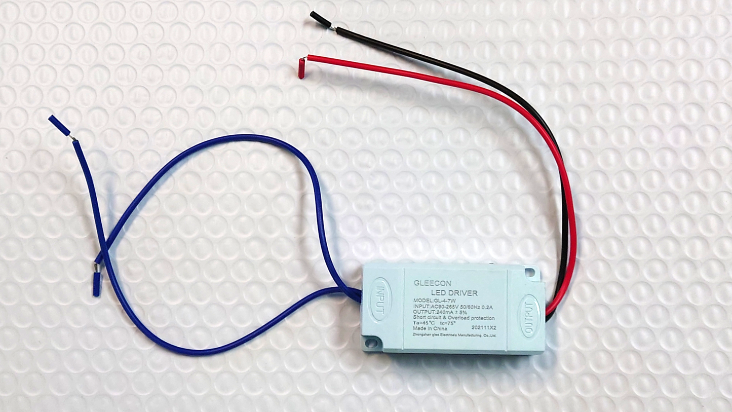 A replacement LED driver with a blue and a red wire, and a label indicating the model and electrical specifications.