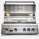 A stainless steel gas grill with the lid open, showing four control knobs, blue flame indicators, and interior grates on a white background.