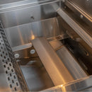 Close-up of a stainless steel grill or smoker interior with a metal grate on the left and a central metal divider or tray.