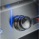 Close-up of a stainless steel outdoor grill control knob with a blue flame indicator light glowing on a brushed metal surface.