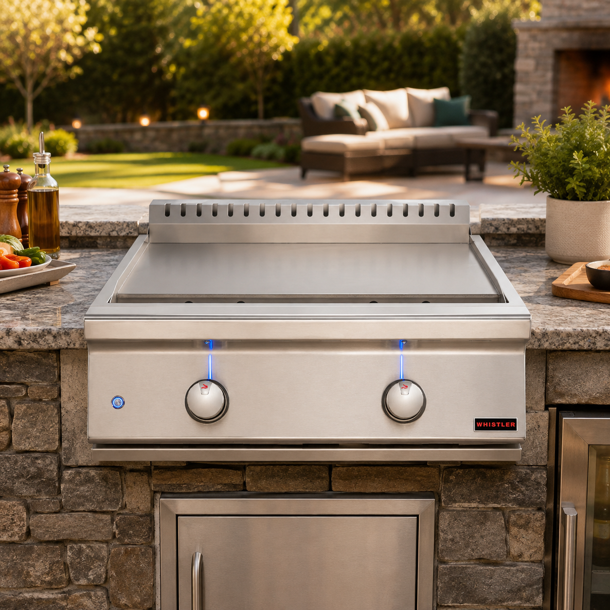 A stainless steel built-in burner griddle set into a stone outdoor kitchen counter. The grill features two control knobs with blue indicator lights and a small red 'MASON' brand logo on the front right.